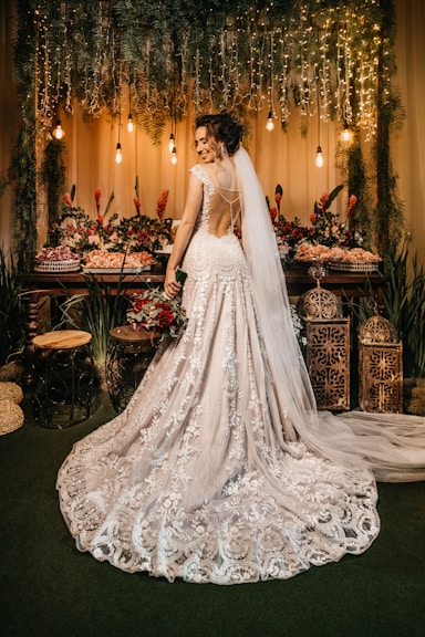woman in white wedding dress standing beside red roses