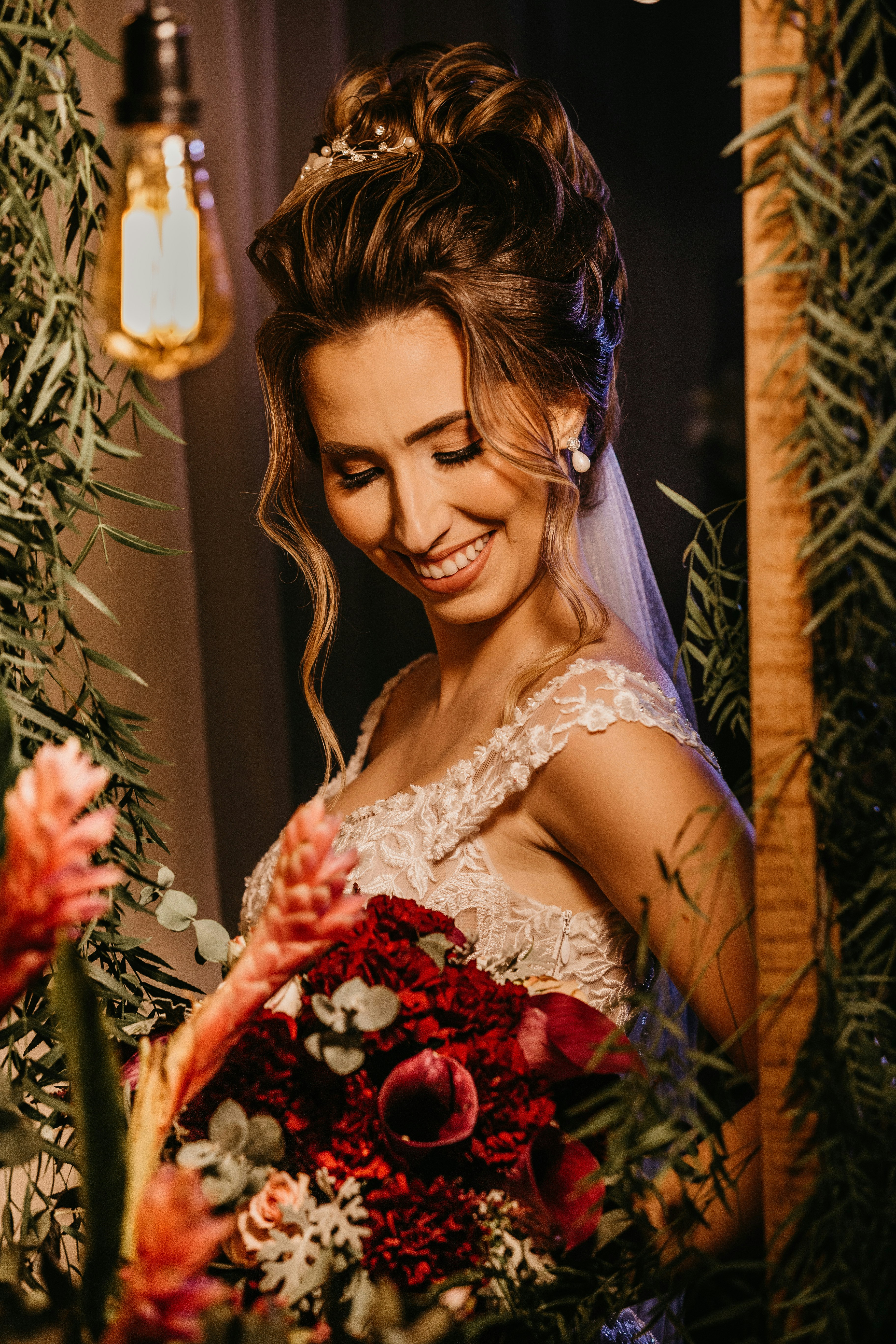 woman in white floral lace wedding dress holding red rose bouquet