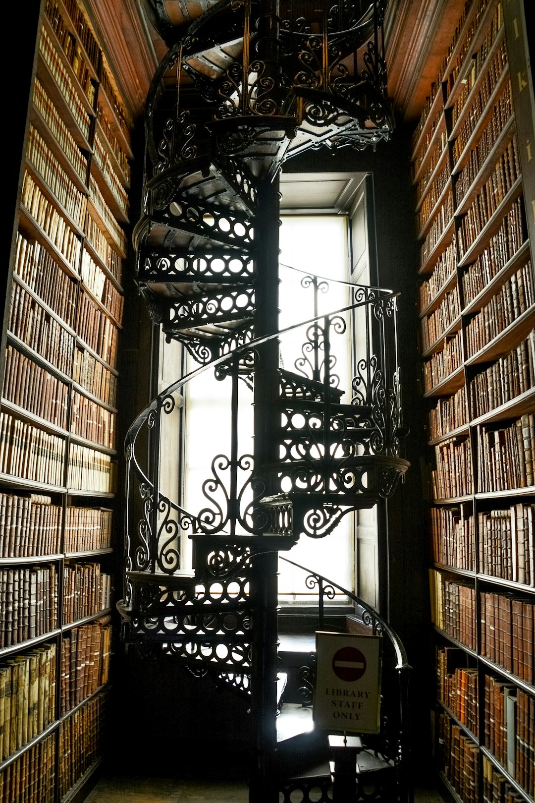 black metal spiral staircase near brown wooden book shelves