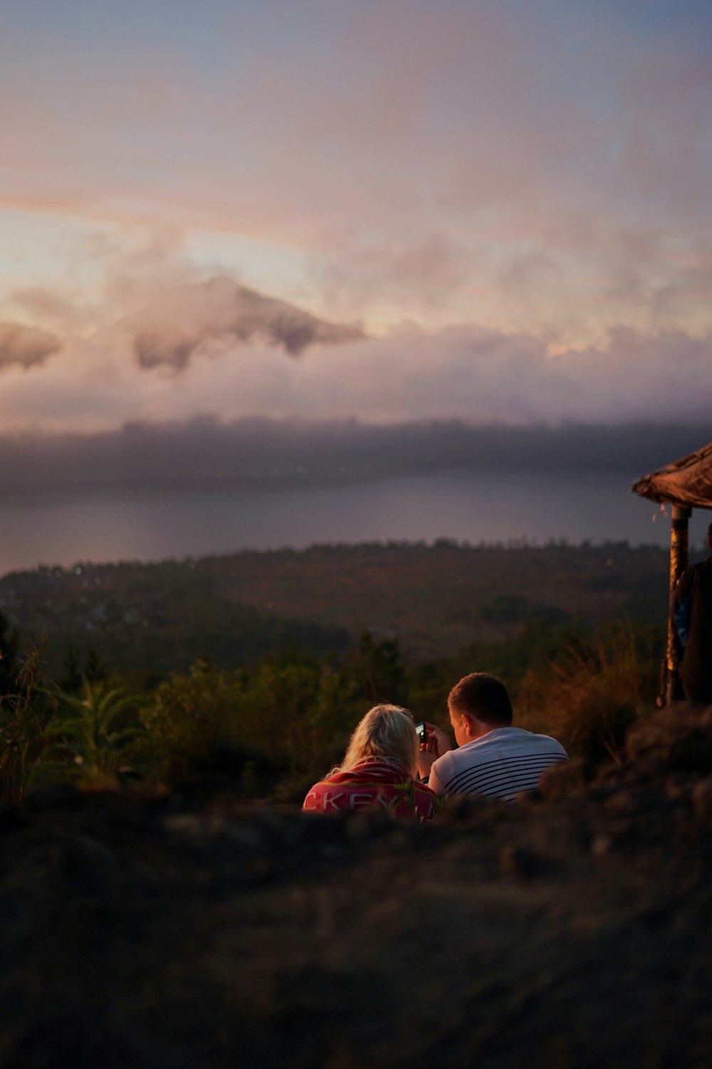 couple sitting on ground near brown wooden house during daytime