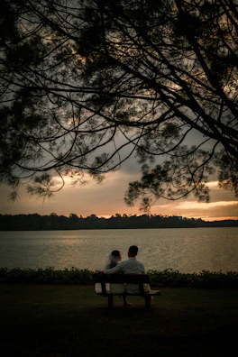 A serene couple seated on a rustic bench, bathed in charcoal-gray twilight, sharing a quiet moment.