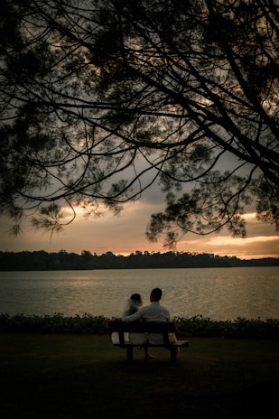A happy couple sharing a laugh on a cozy park bench during sunset.