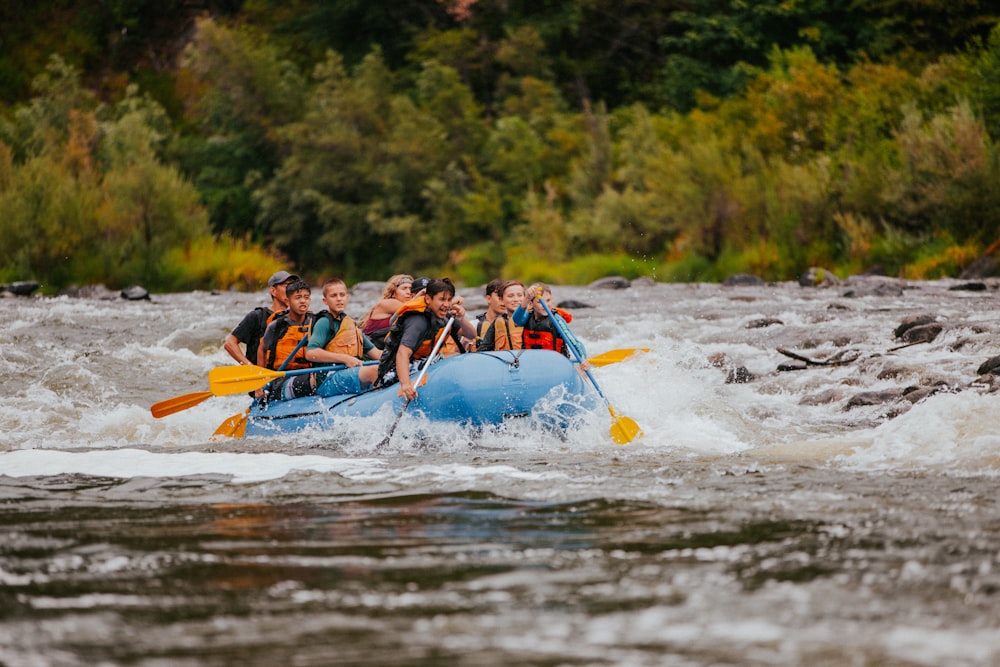 Menschen, die tagsüber auf dem blauen Kajak auf dem Fluss fahren