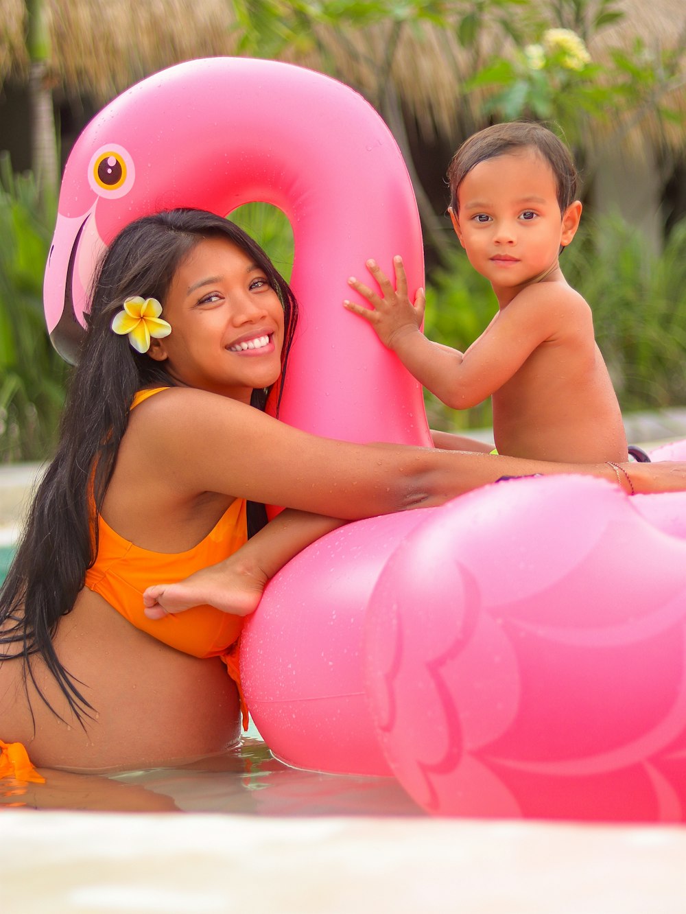 girl in orange bikini top holding pink inflatable balloons