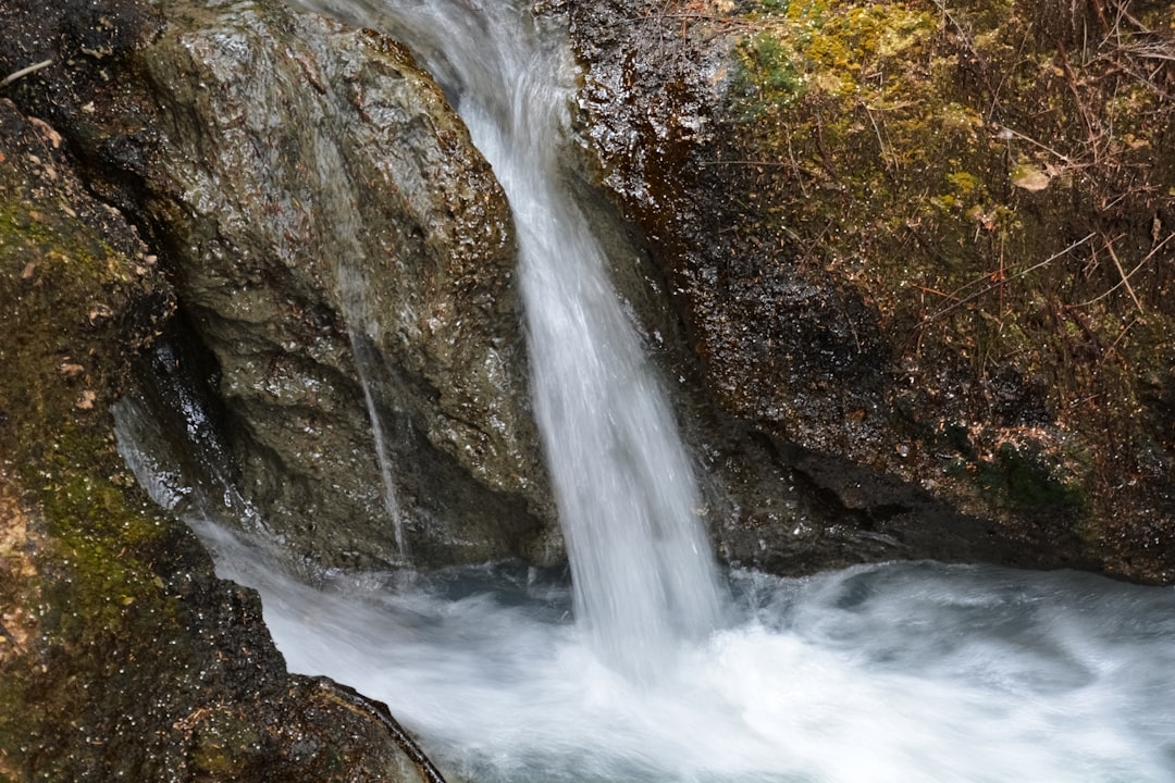 water falls on brown rocky mountain during daytime