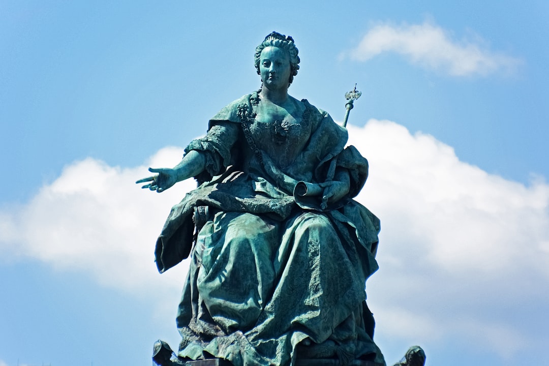 man holding sword statue under blue sky during daytime