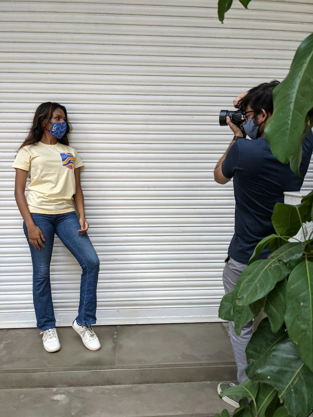 Frau in gelbem Hemd und blauer Jeans mit schwarzer DSLR-Kamera