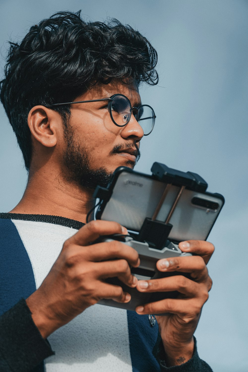 man in blue and white sweater holding black smartphone