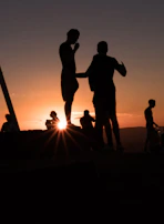 Sunset silhouette of the team standing tall on a hill, symbolizing growth and achievement.