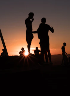 Sunset silhouette of the team standing tall on a hill, symbolizing growth and achievement.