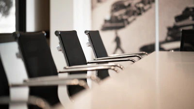 Black office chairs with chrome arms in a row at a conference table