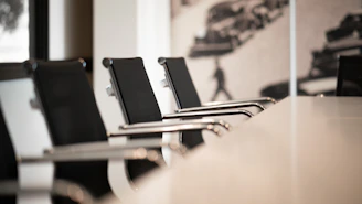 Black office chairs with chrome arms in a row at a conference table