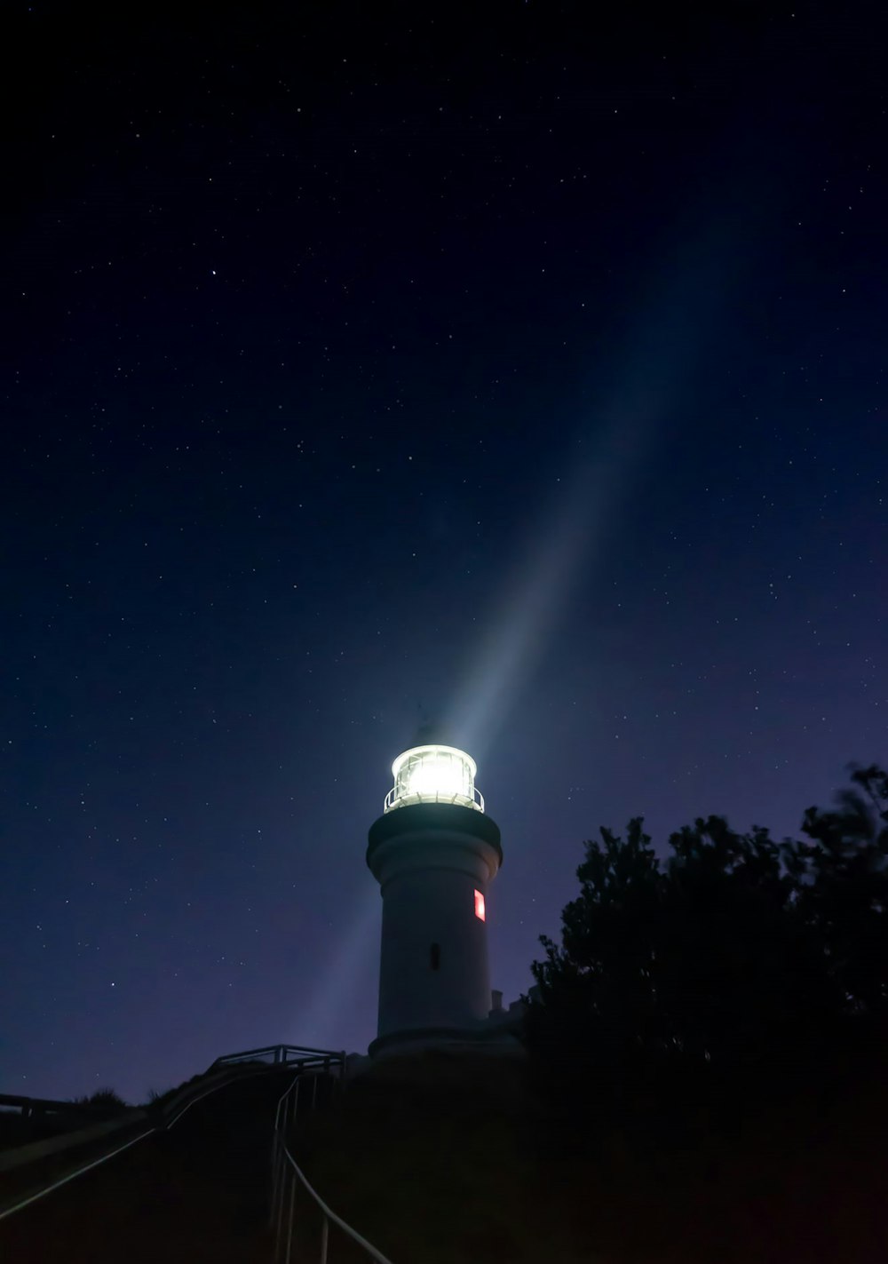 Torre de luz blanca y negra bajo el cielo azul durante la noche