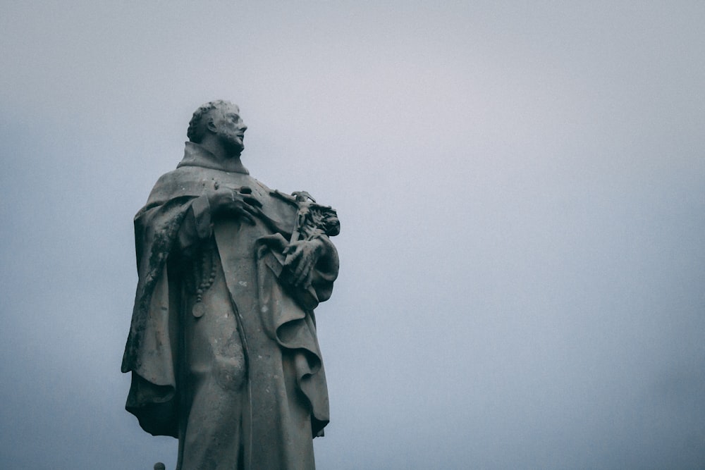 man holding a book statue