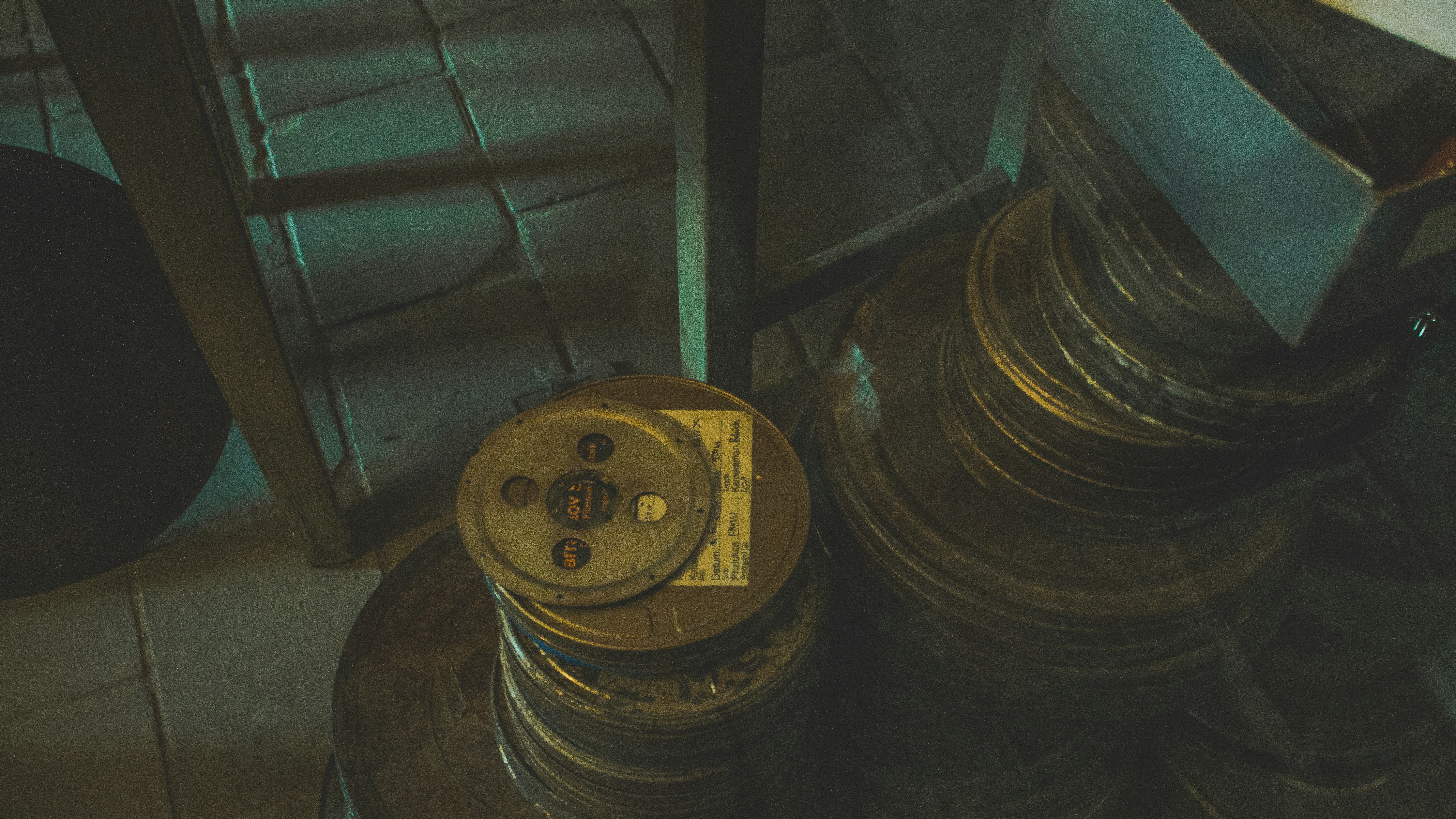 Vintage 35mm film reels stacked on dark table, dramatic warm side lighting, deep shadows