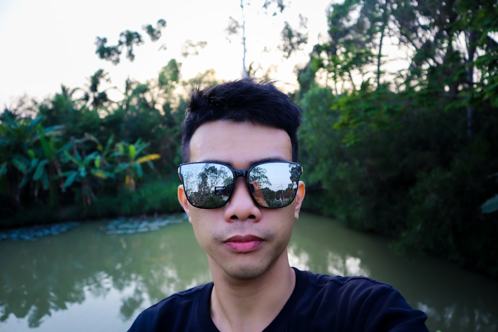 Homme en chemise noire à col rond portant des lunettes de soleil noires