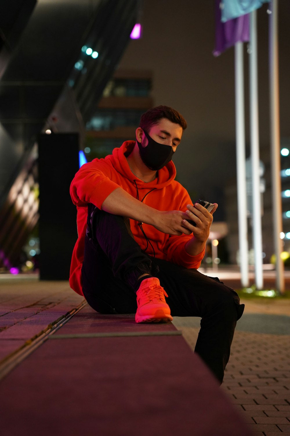 man in red jacket and black pants sitting on floor