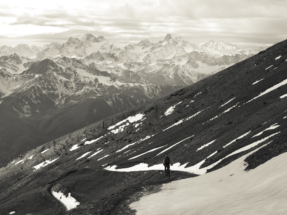 Persona in piedi su un terreno coperto di neve vicino a una montagna coperta di neve durante il giorno