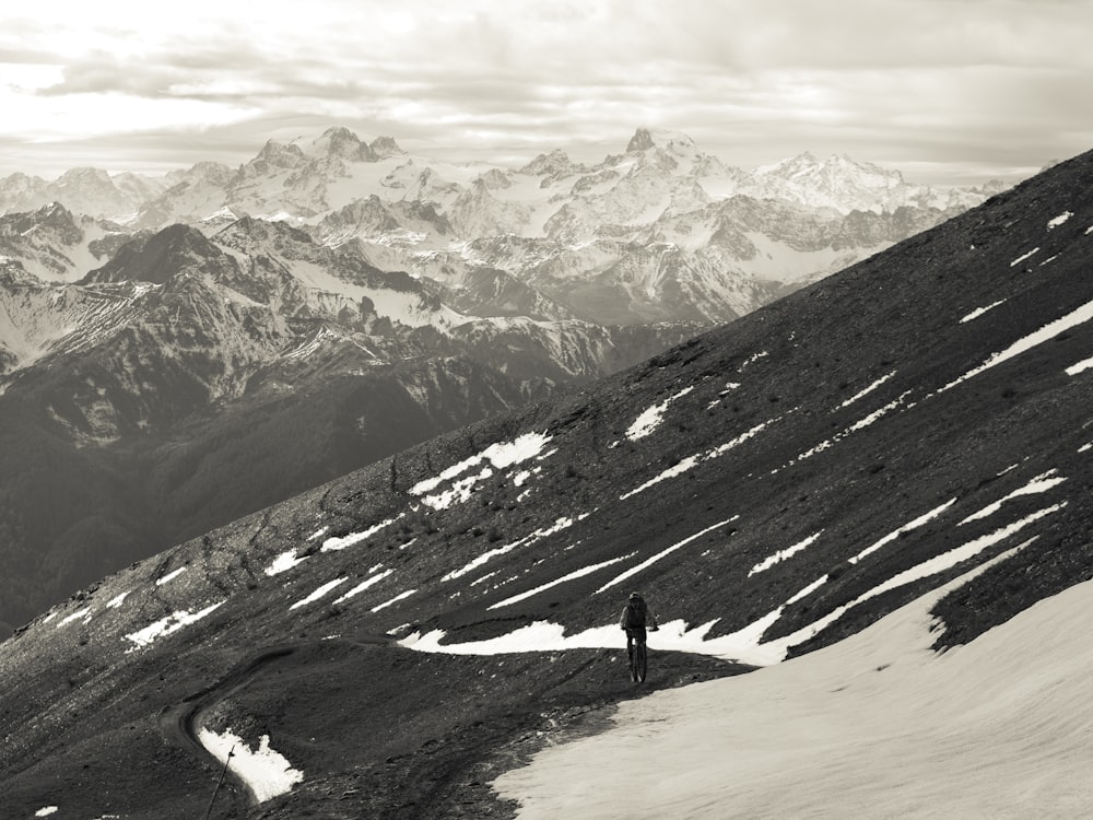 personne debout sur un sol enneigé près d’une montagne enneigée pendant la journée