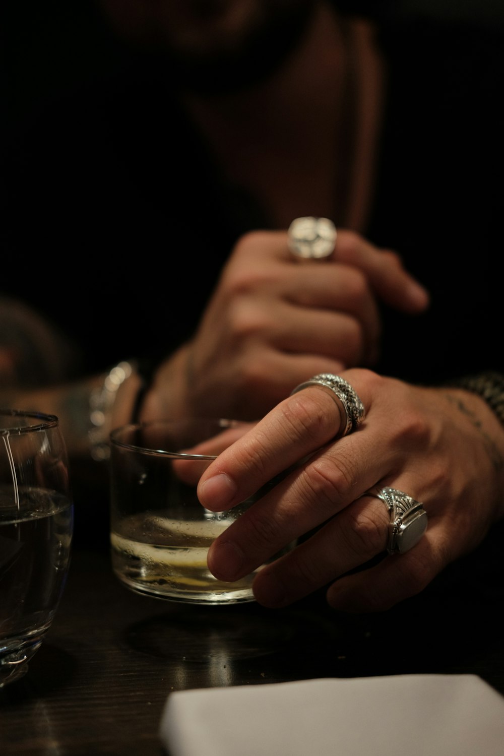 person wearing silver ring holding clear drinking glass