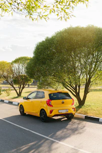 yellow sedan on gray asphalt road during daytime