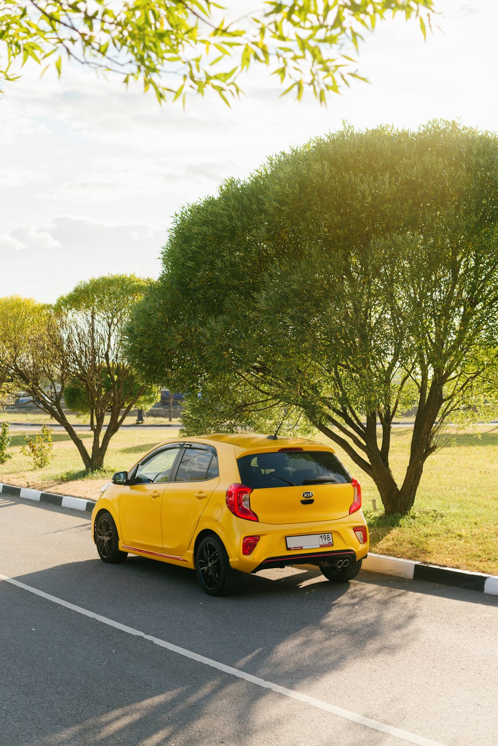 yellow sedan on gray asphalt road during daytime