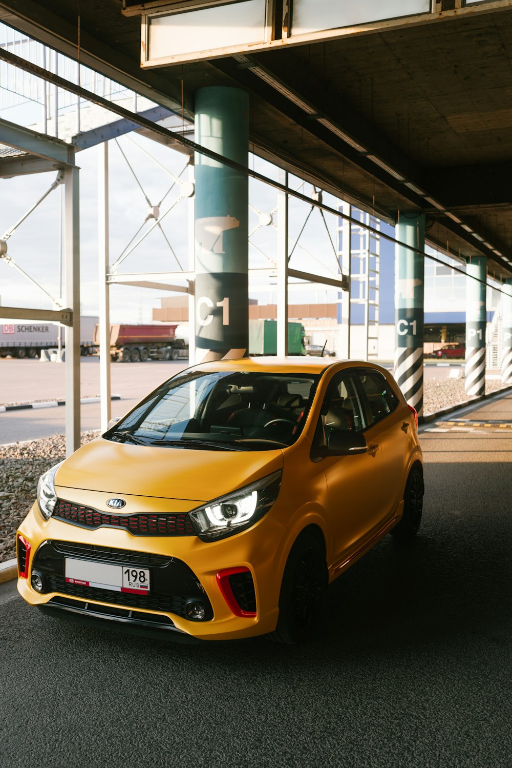 yellow car parked near white and gray post