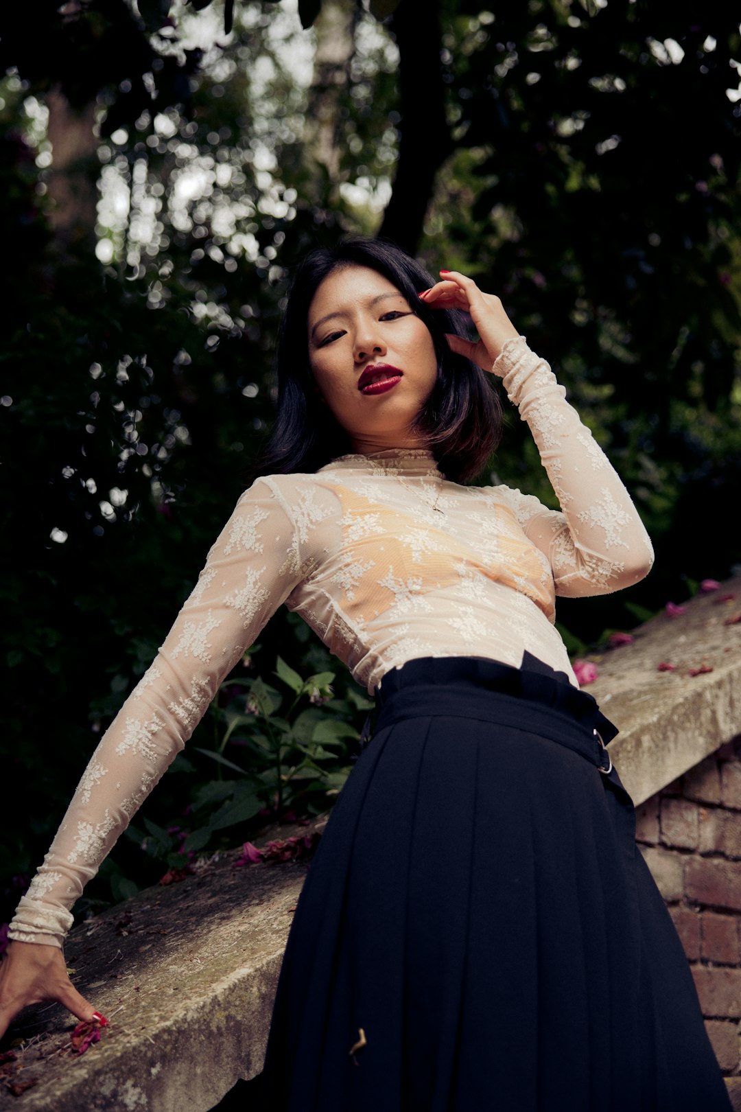 woman in beige long sleeve shirt and black skirt sitting on brown concrete stairs