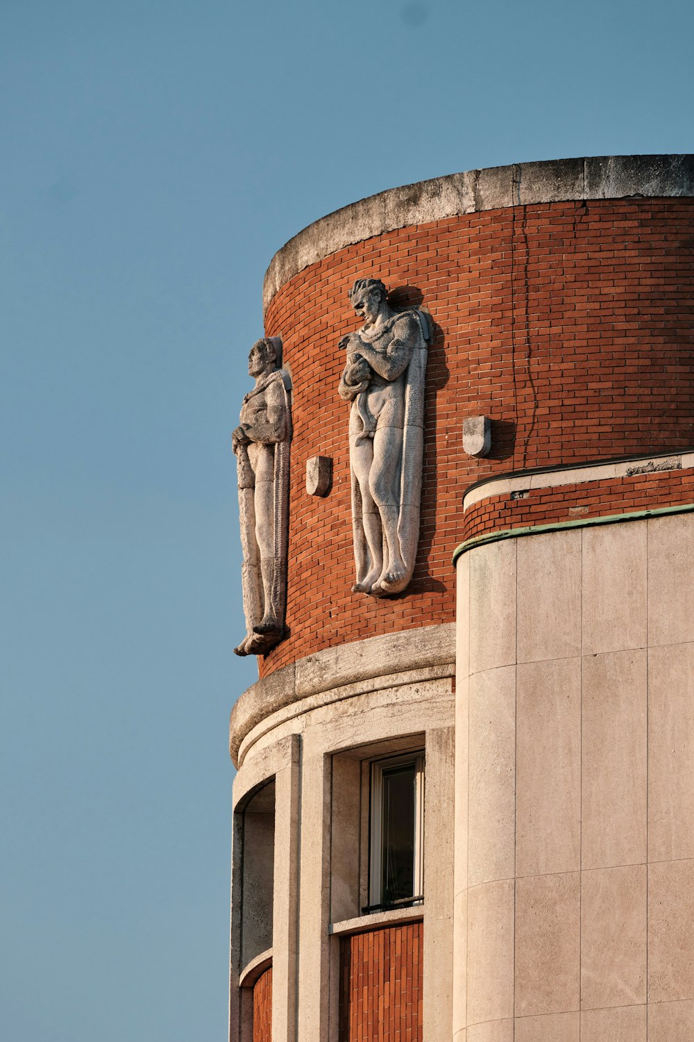 Statue d’homme en robe au sommet d’un bâtiment en béton brun