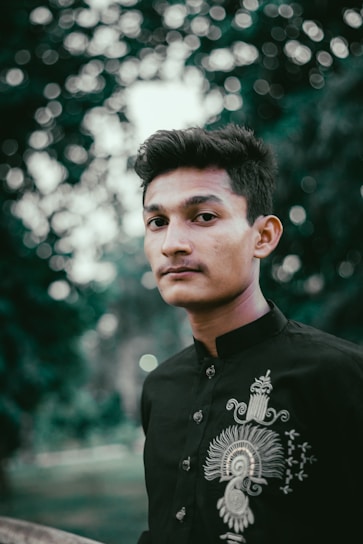 A young Indian man wearing a soft bamboo shirt, standing confidently in a natural outdoor setting.