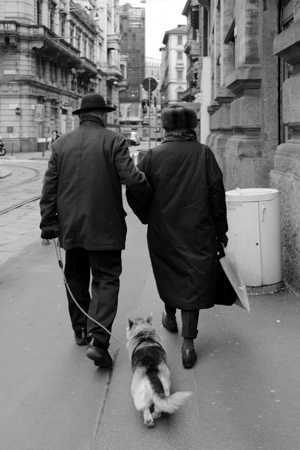 man in black coat walking with dog on street
