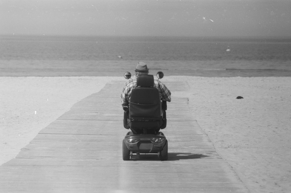 grayscale photo of man riding motorcycle on road