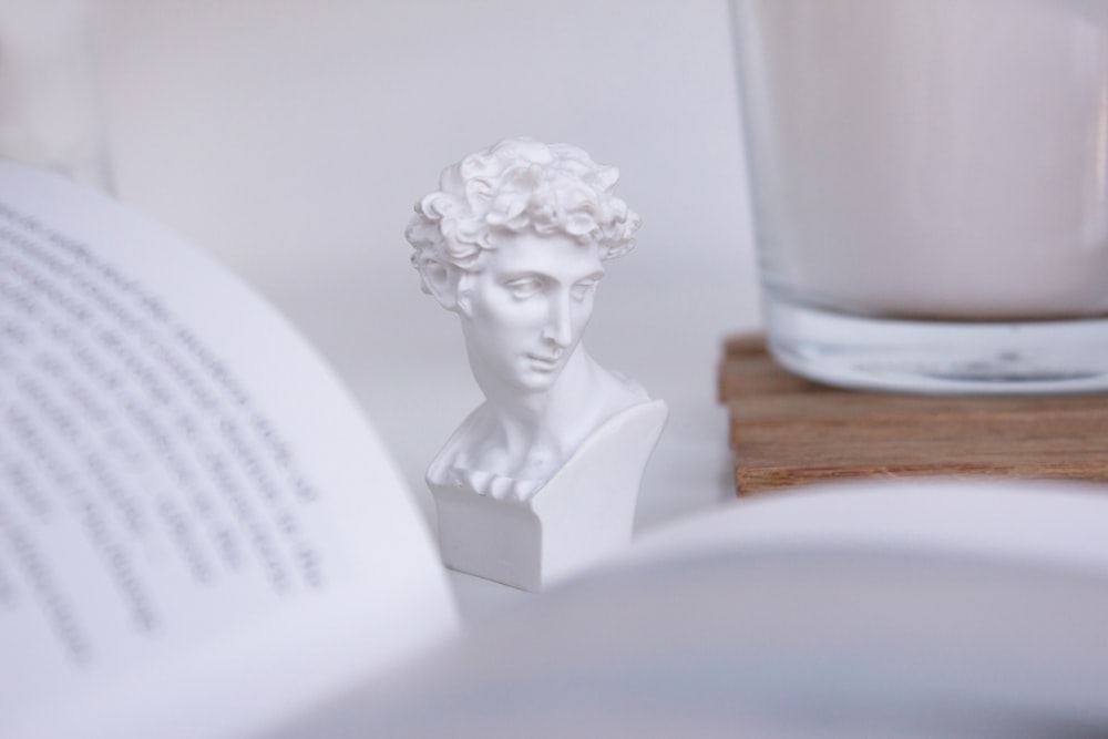 white ceramic woman figurine on brown wooden table