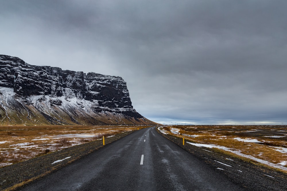 gray asphalt road near gray rocky mountain under gray sky during daytime