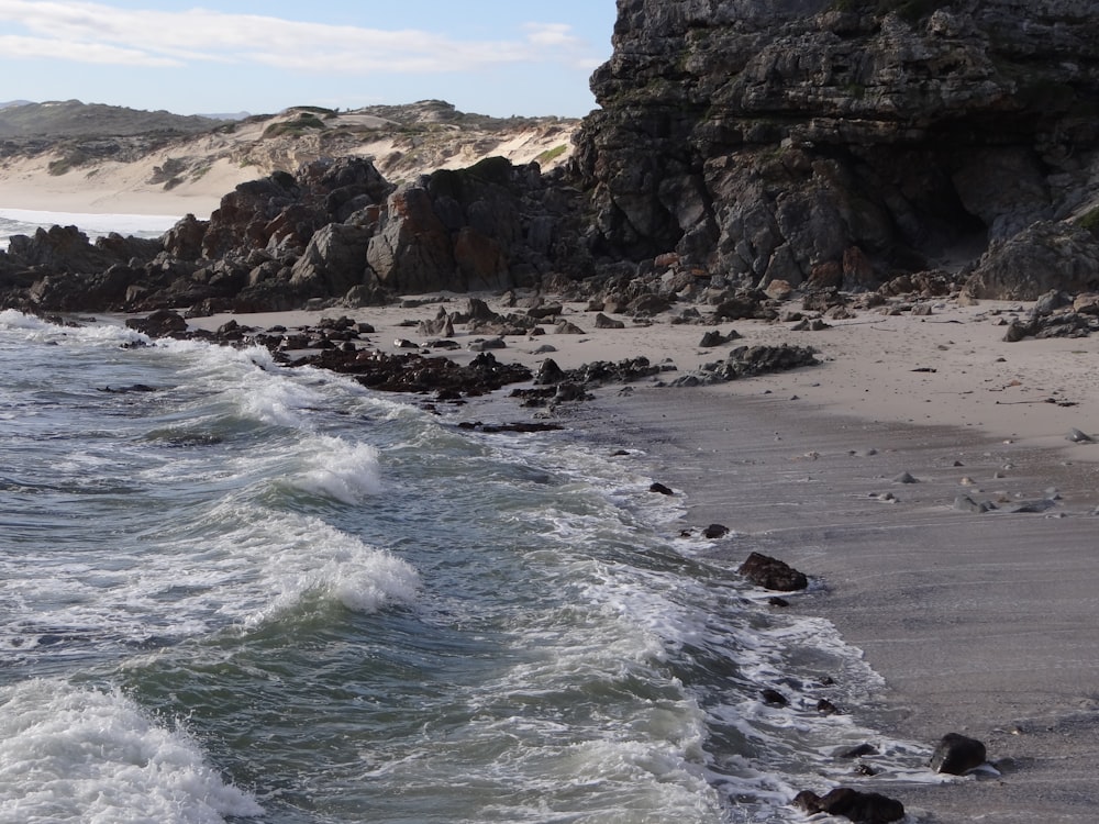 sea waves crashing on rocky shore during daytime