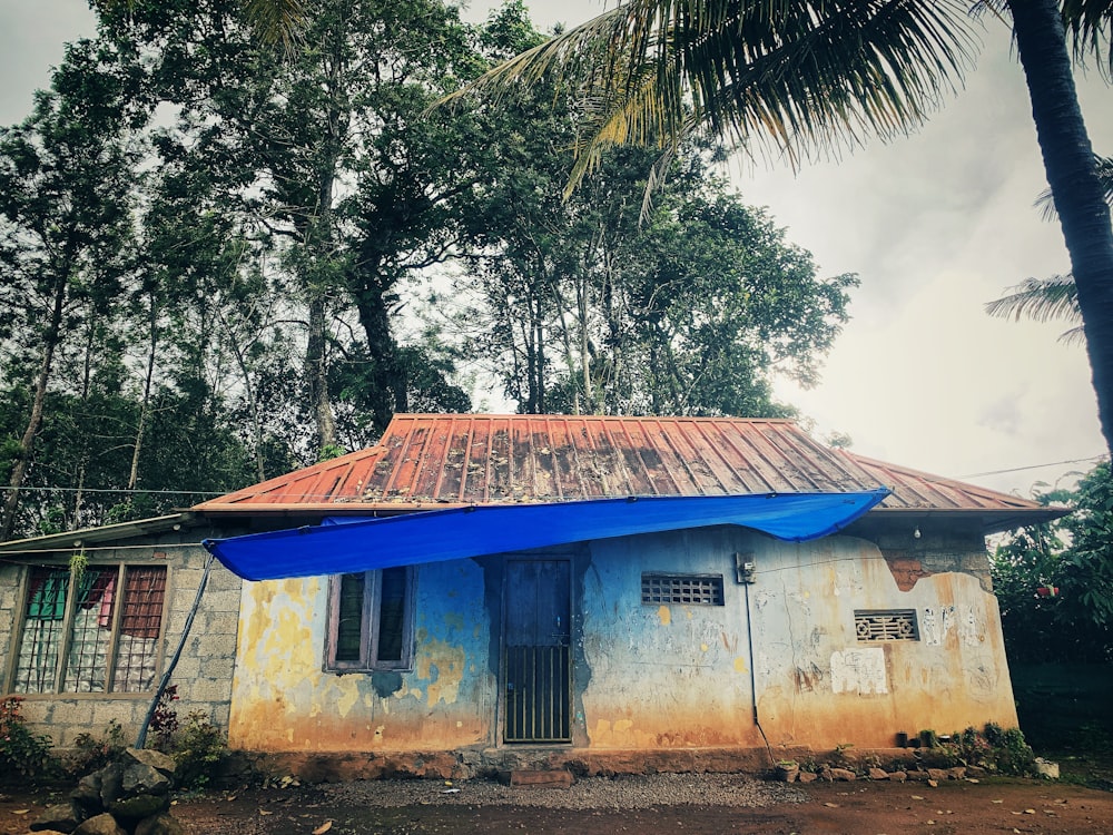 Casa de hormigón azul y blanco cerca de árboles verdes durante el día