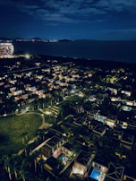 A nighttime aerial view of a luxury real estate property illuminated with subtle blue accent lights.