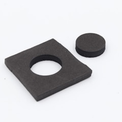 A black rectangular foam piece with a circular cut-out alongside a separate circular foam piece. The rectangular piece appears to be the source of the circular piece.