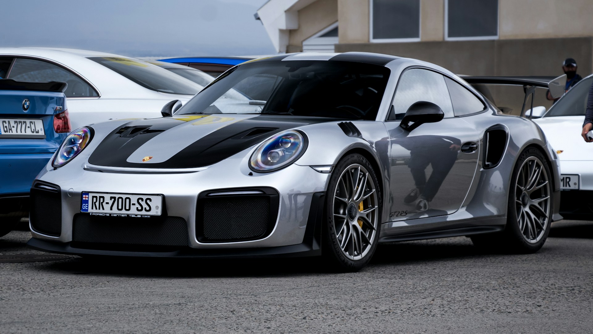 silver porsche 911 parked in front of white building