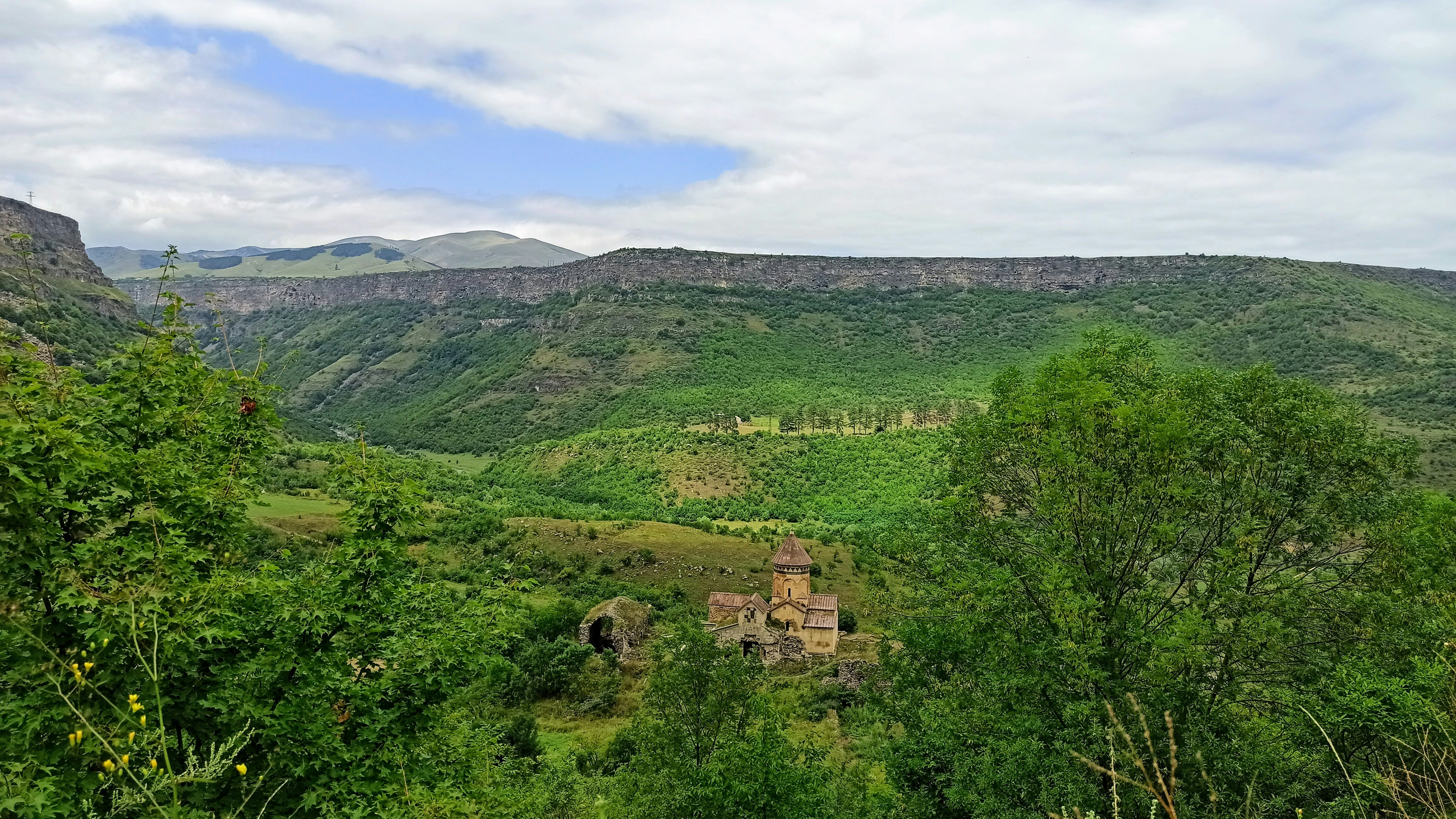 Remote mountain valley with cedar forest and stone meditation hall nestled among steep rocky cliffs