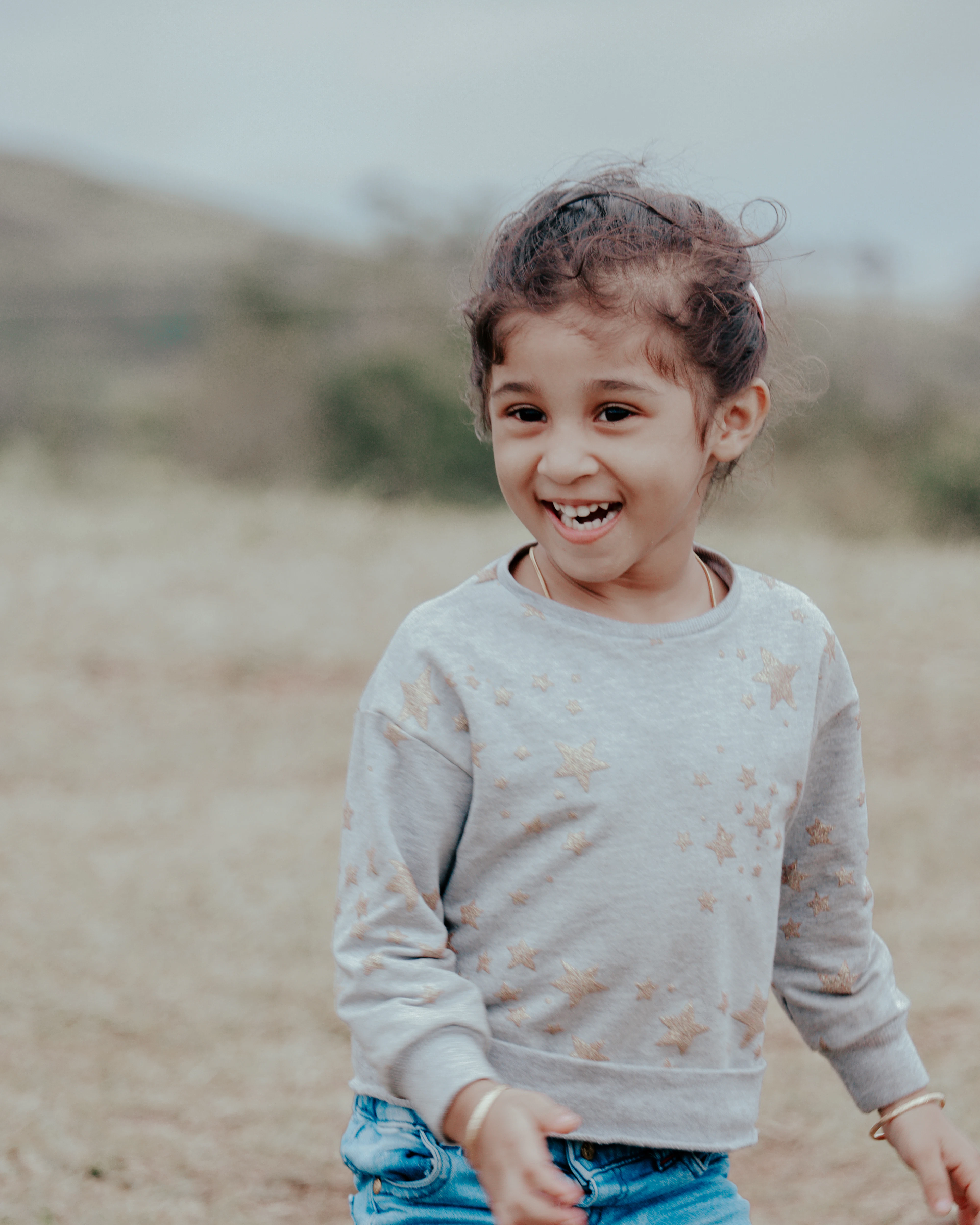 Smiling girl in a soft grey crew-neck sweatshirt and jeans