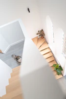 A multi-level cat playground featuring natural wood and soft pastel fabrics, designed to fit under a modern staircase.