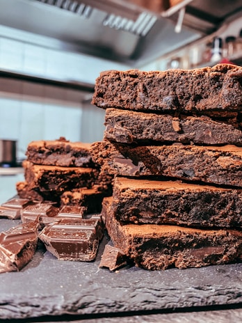 A rustic wooden board displaying rich chocolate brownies dusted with powdered sugar.