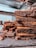 A stack of rich, chocolatey brownies is placed on a slate board, with chunks of dark chocolate scattered around. The brownies have a dense, moist texture, and the background includes a blurred view of a kitchen setting.