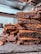 A stack of rich, chocolatey brownies is placed on a slate board, with chunks of dark chocolate scattered around. The brownies have a dense, moist texture, and the background includes a blurred view of a kitchen setting.