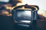 A stylish smart watch resting on a black surface with soft lighting.