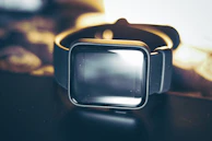 An elegant smartwatch resting on a minimalist black surface with subtle reflections.