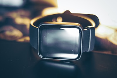 A stylish smart watch resting on a black surface with soft lighting.