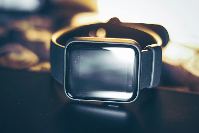 A sleek black smartwatch glowing softly against a deep black background, highlighting its luxury design.