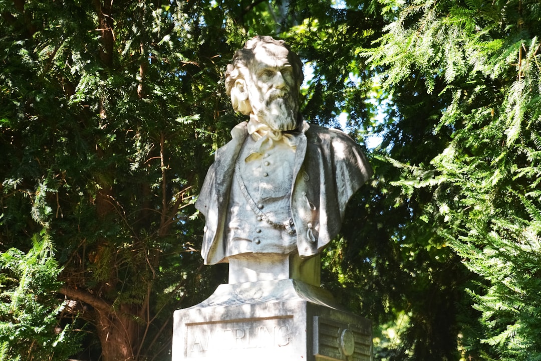 woman in dress statue near green trees during daytime